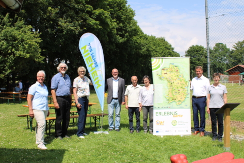 Acht Menschen stehen im Halbkreis, lächelnd mit einem großen Poster der Erlebniskarte und einem Nieheimer Banner auf einer Wiese